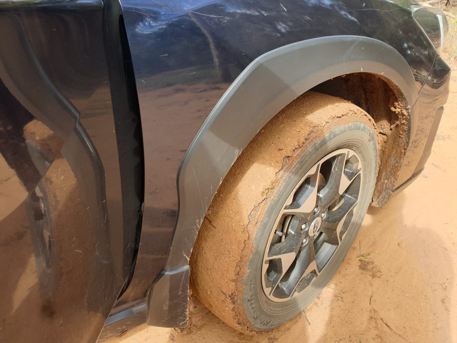 The wet dirt sticks to the car tyres
